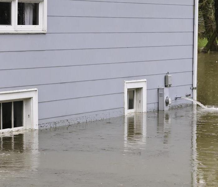 The side of flooded suburban house with water being pumped out