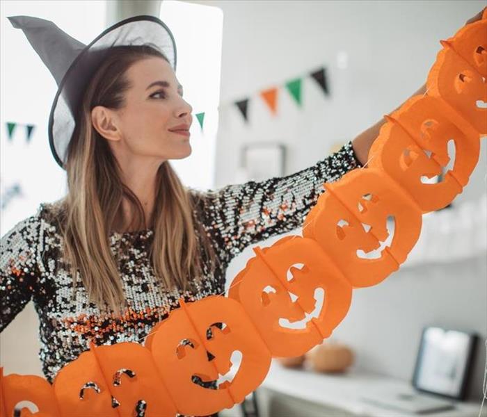 woman in costume decorating home for Halloween